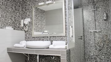 Un baño moderno con un espejo grande, un lavabo y una ducha.