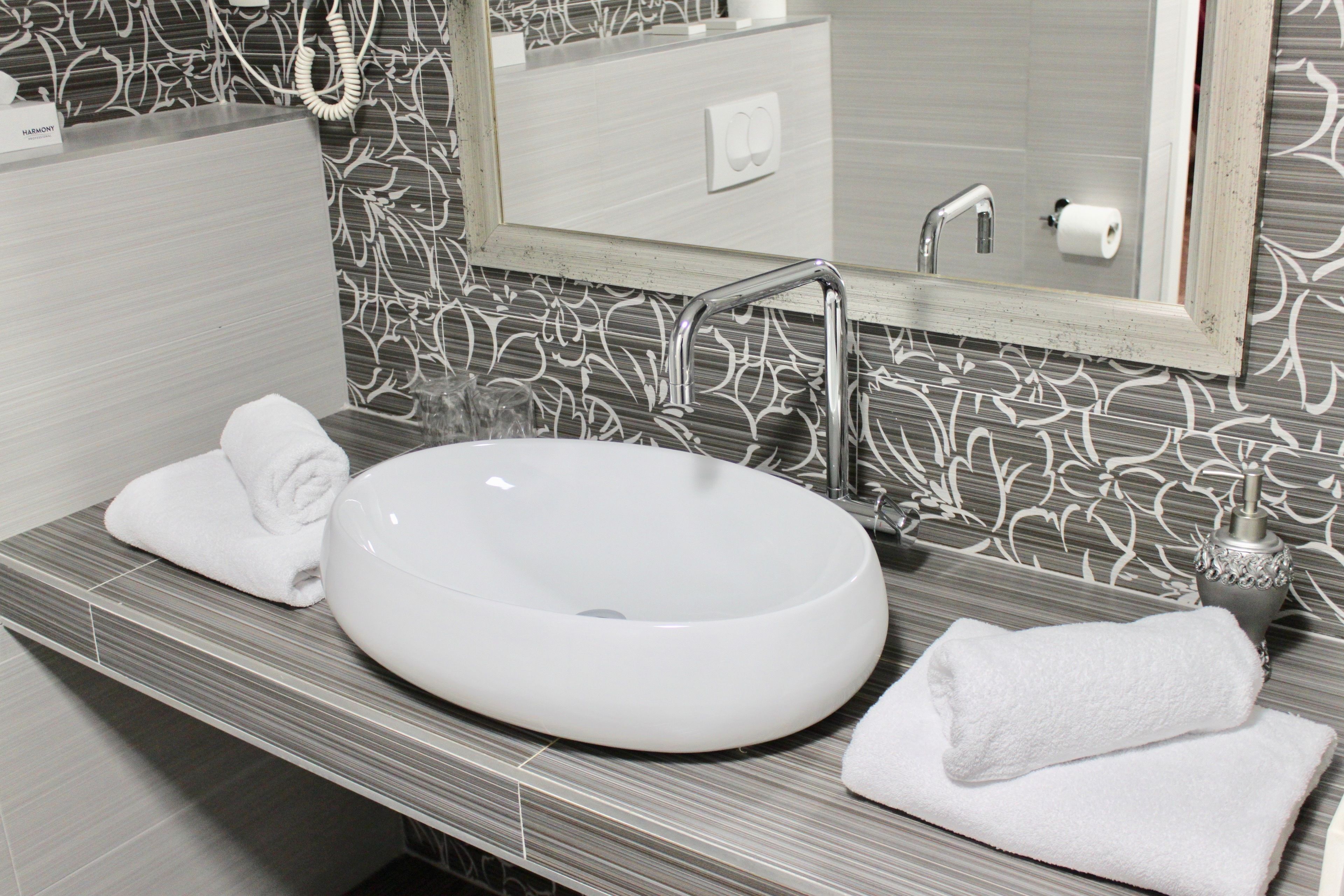 A bathroom with a large white sink, a mirror, and a towel on the counter.