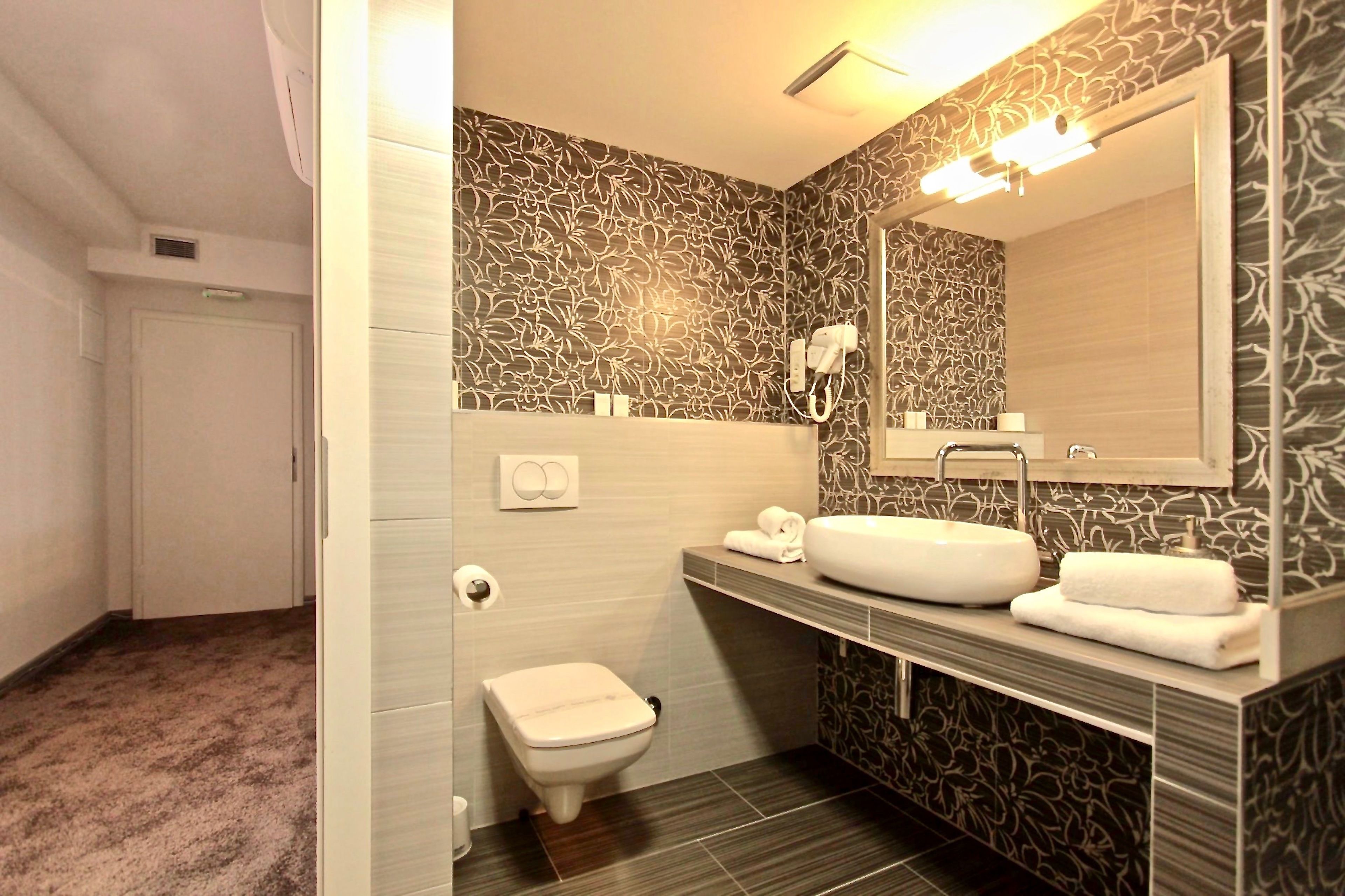 A bathroom with a toilet, a sink, and a mirror.