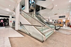 Ein modernes Einkaufszentrum mit einer zentralen Rolltreppe, umgeben von Geschäften.