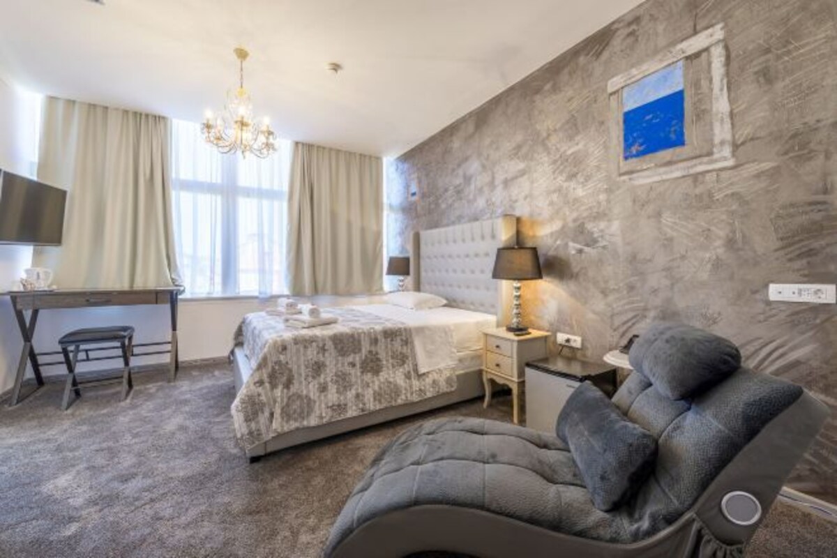 Habitación de hotel con cama, escritorio, silla, televisión y una obra de arte colgada en la pared.