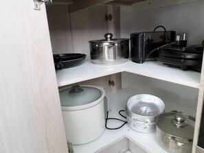 Una cocina con encimera blanca, cafetera, hervidor, cocedor de arroz y tostadora.