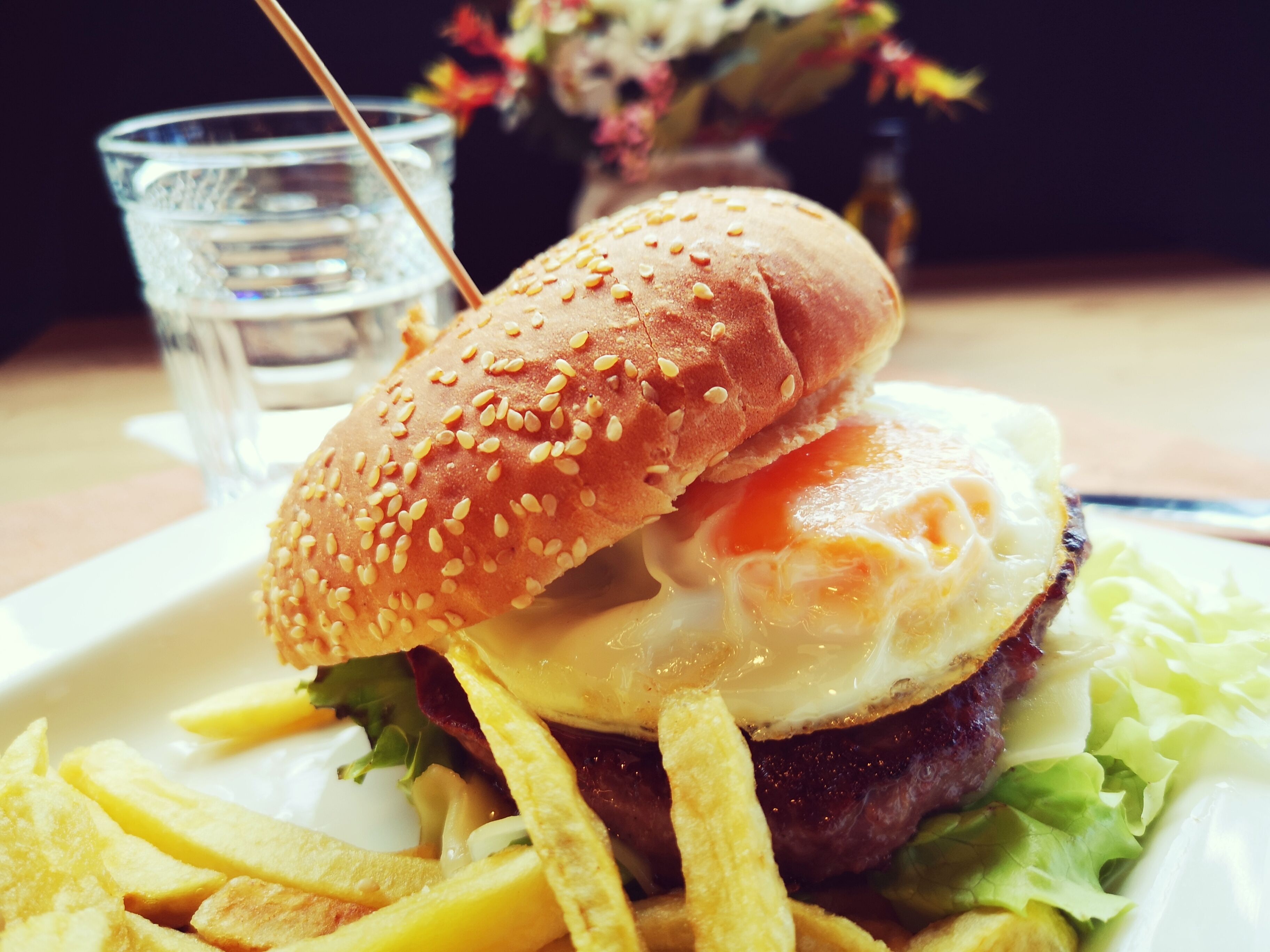 Una comida con una hamburguesa, papas fritas y una bebida sobre una mesa.