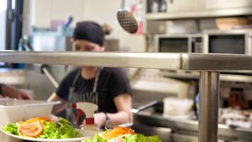 Un plan de travail de cuisine avec deux assiettes de salade, un chef cuisinier en arrière-plan et des appareils de cuisine.
