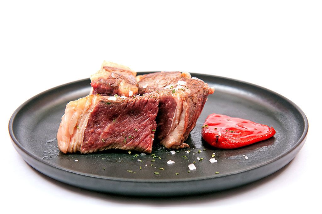 Un plat amb carn tallada i una làmina de tomàquet.