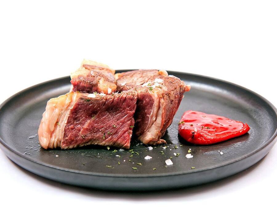 Un plat amb carn tallada i una làmina de tomàquet.