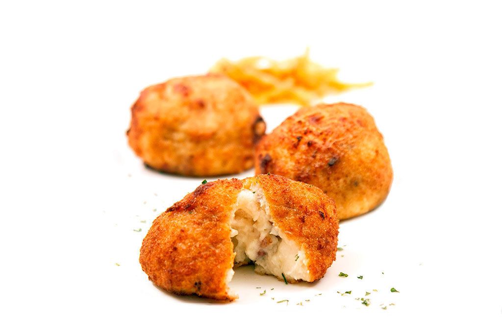 Tres porciones de comida empanizada y frita, posiblemente croquetas, acompañadas de papas fritas.