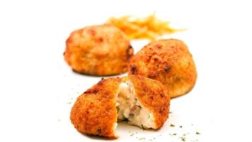 Drie gebakken en gepaneerde snacks, mogelijk kroketten, met frietjes.