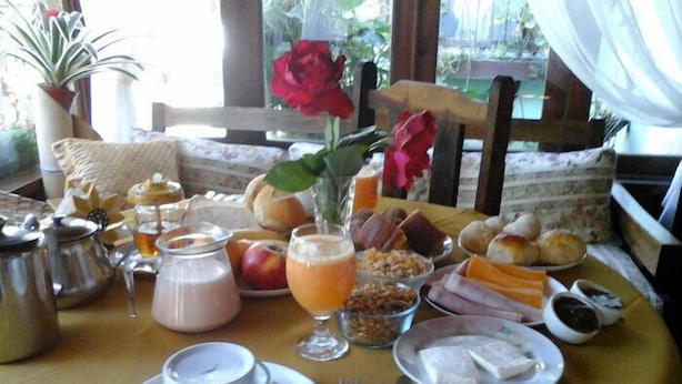 Una mesa de desayuno con diversos alimentos, una tetera y una taza de café.