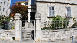 Un edificio de piedra con una verja metálica y escalones que conducen a una puerta.