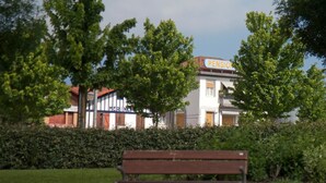 A bench in a park with a building labeled "PENSION" in the background. - HOSTAL EUROPA pensión (Irun)