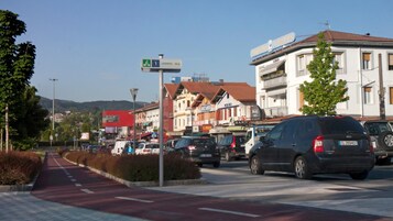 A street view with a red bike lane, parked cars, and buildings with signs like "RICARD" and "Mansion".