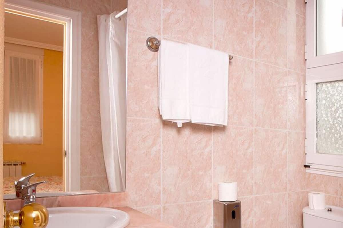 Un baño con lavamanos de mármol, inodoro y ducha.