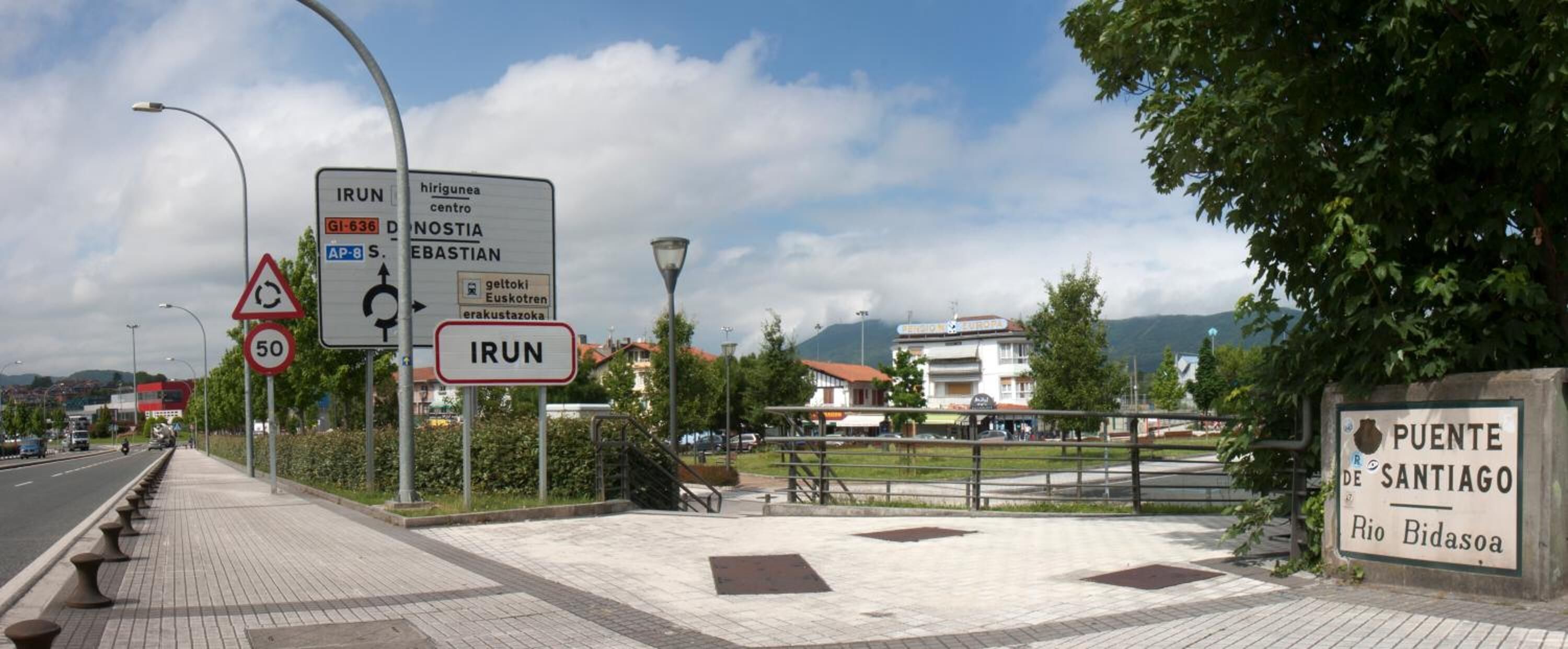 A street sign with directions to IRUN, a roundabout, and a speed limit of 50.