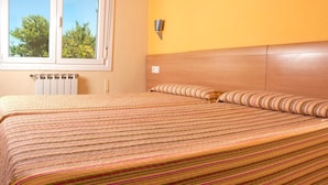A room with a bed, a window, a radiator, and a wall-mounted light fixture. - HOSTAL EUROPA pensión (Irun)