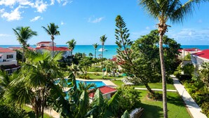 A resort with a pool, palm trees, and a view of the ocean.