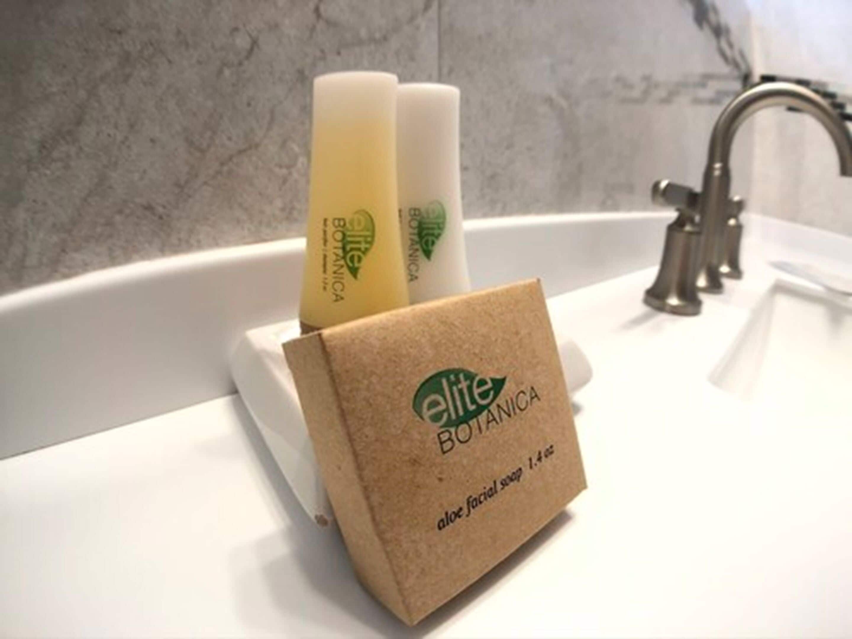 Ein Waschbecken mit zwei Flaschen Elite Botanica Aloe Gesichtsseife und einer braunen Packung desselben Produkts.