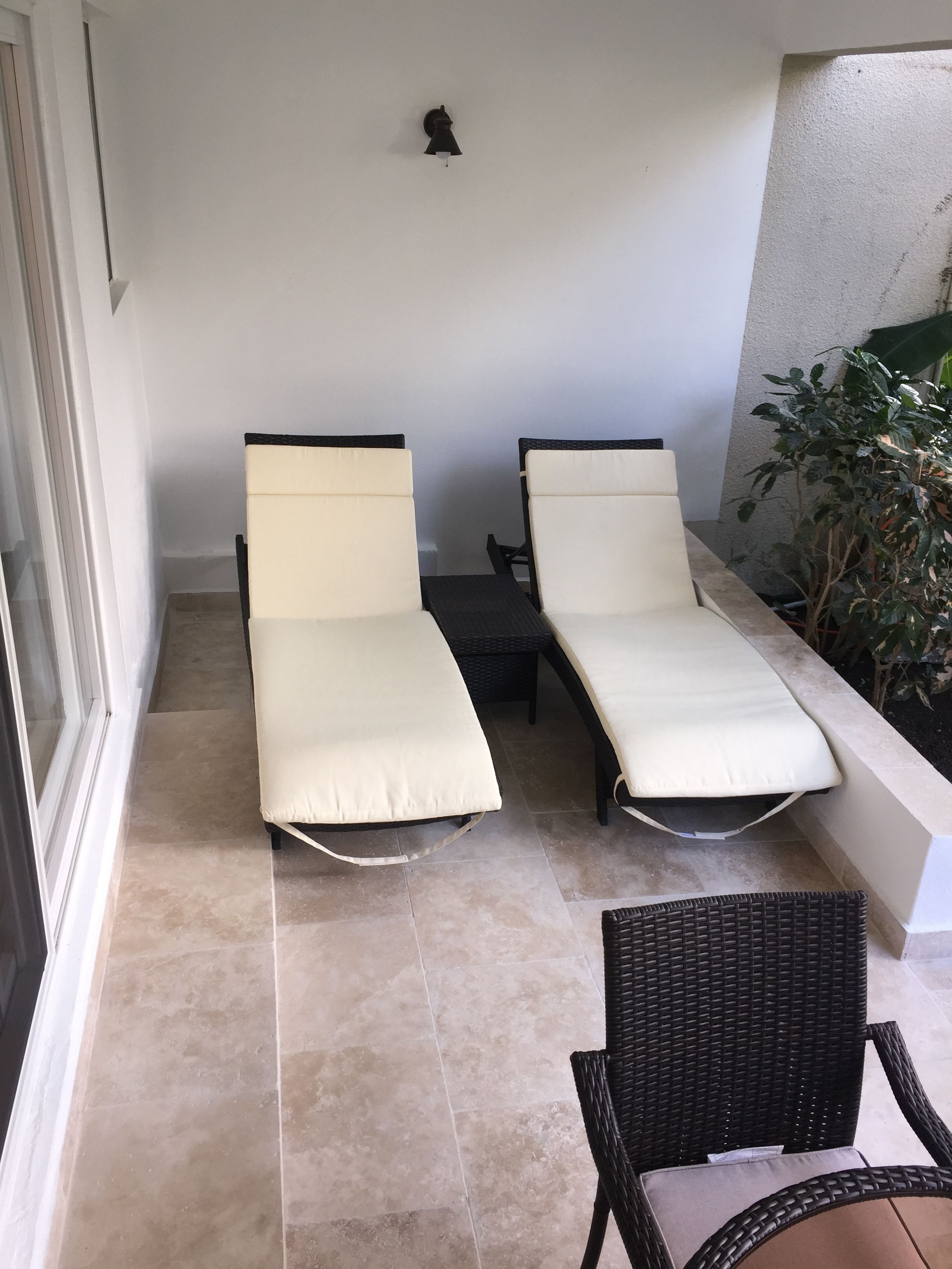 Un balcón con dos sillones de relax y una silla de mimbre.