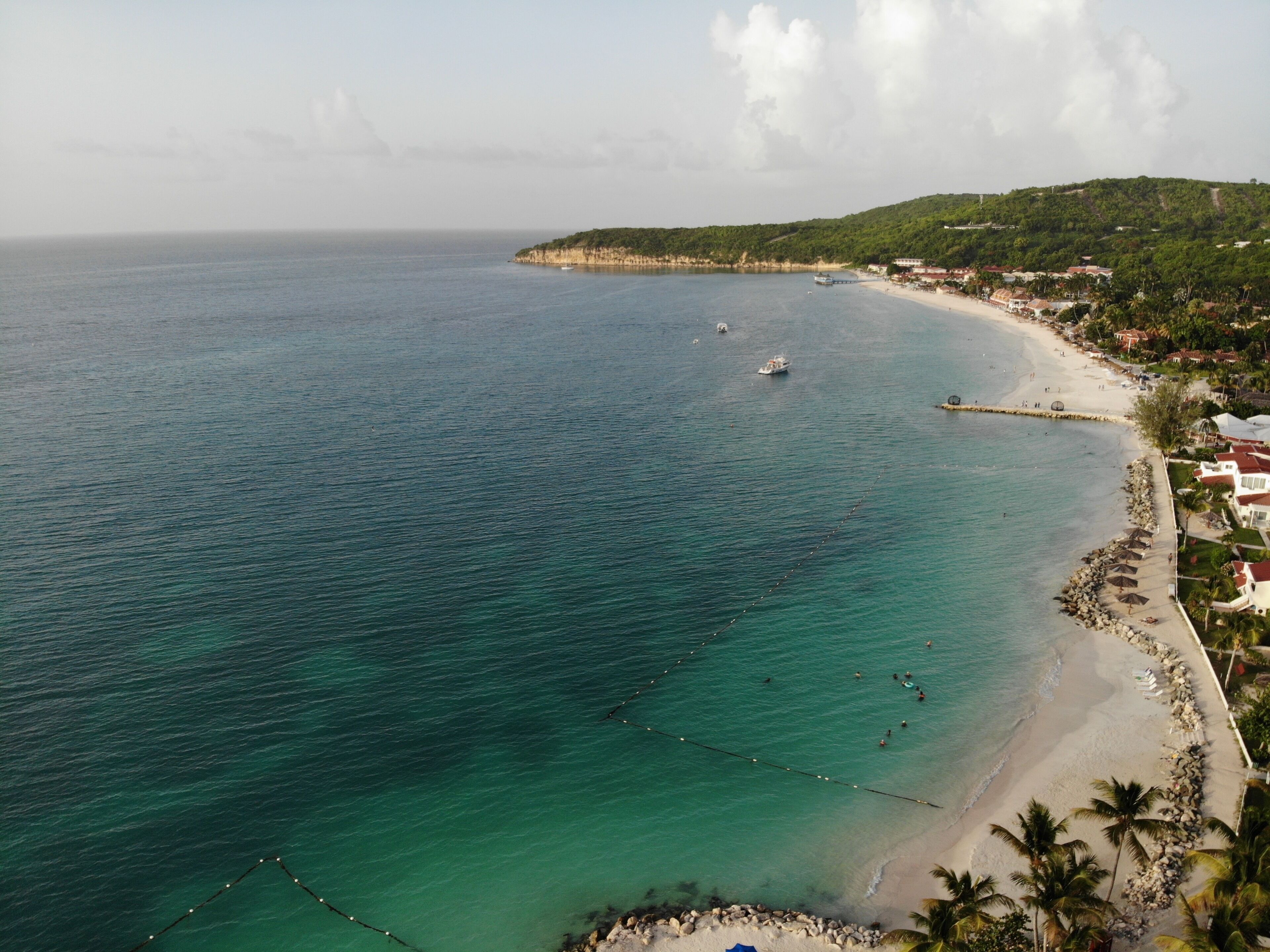 A coastal view with a beach, clear water, and a small boat.