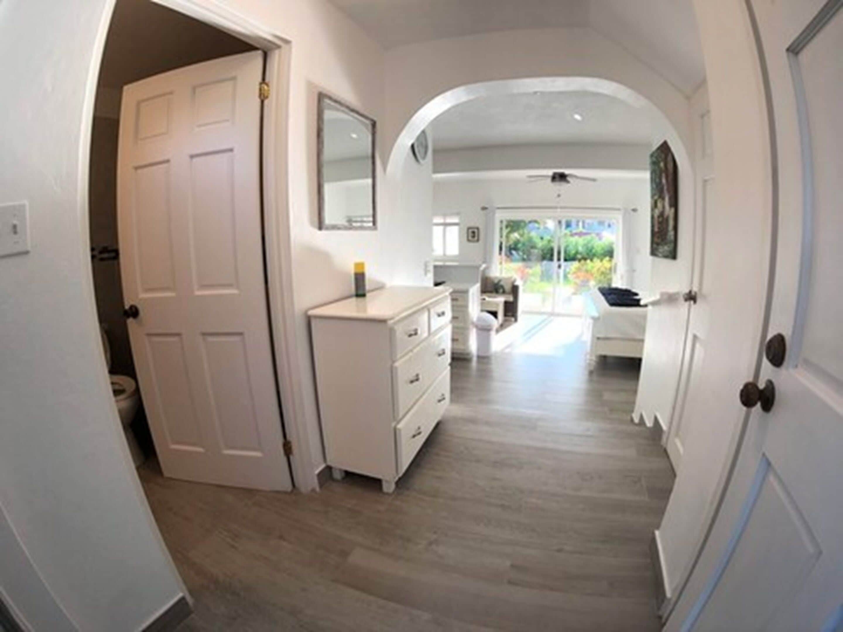A hallway with a white door, a dresser, and a mirror on the wall.