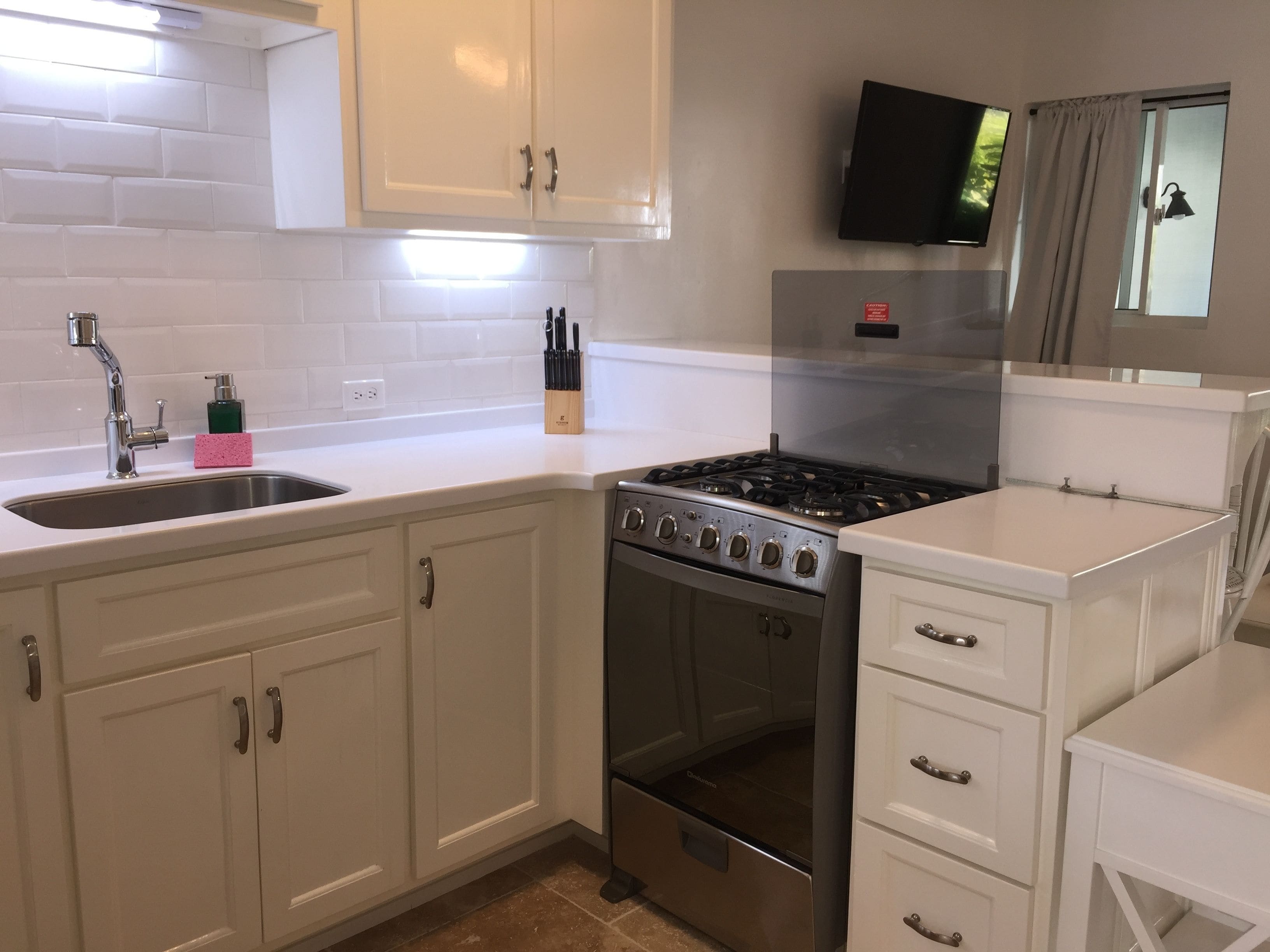 A modern kitchen with white cabinets, a stainless steel stove, and a built-in oven.