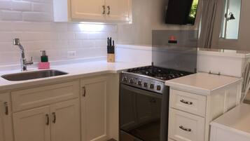 A modern kitchen with white cabinets, a stainless steel stove, and a built-in oven.