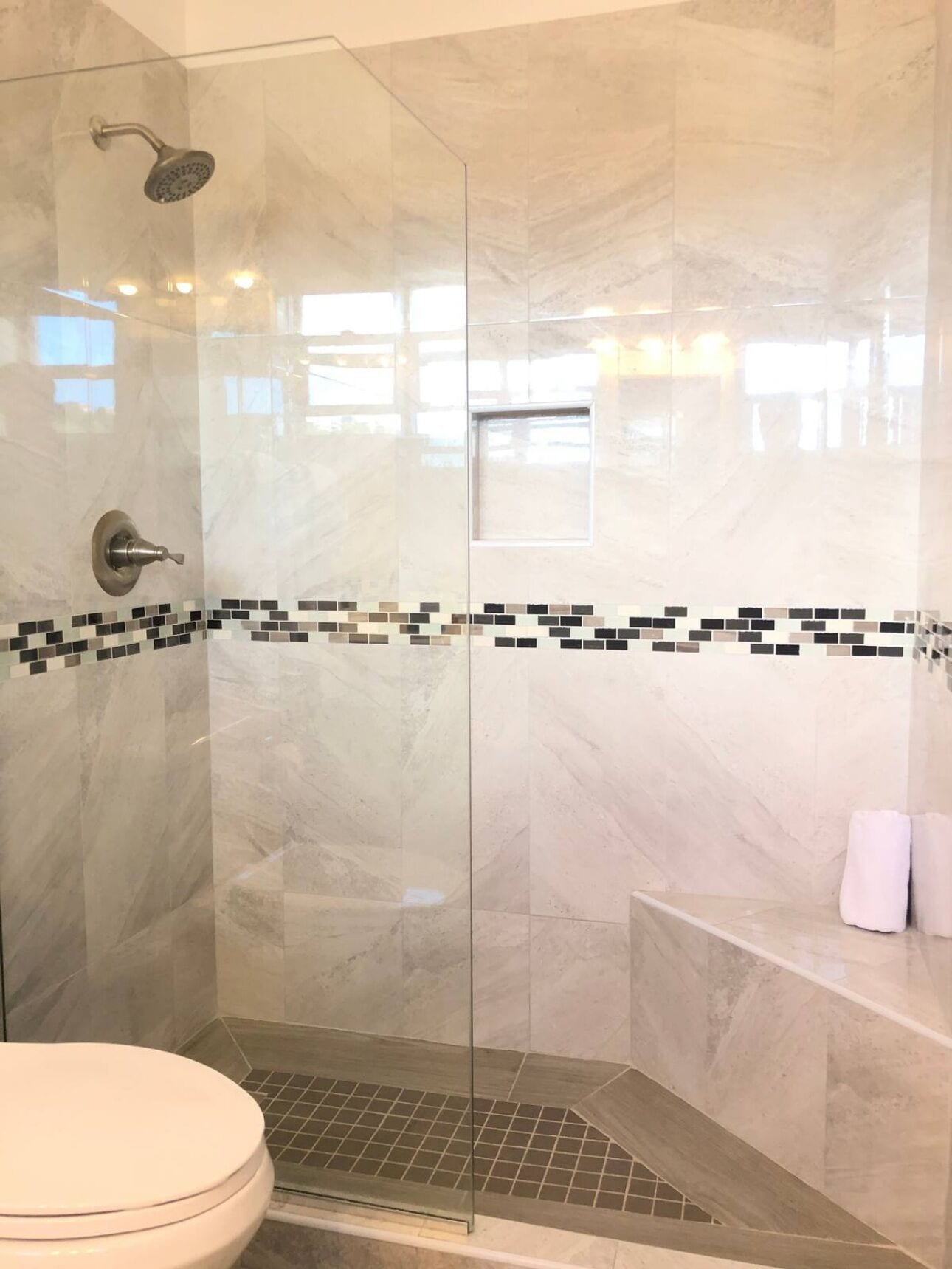 Et moderne badeværelse med en glasafskærmet brusekabine, toilet og badekar.