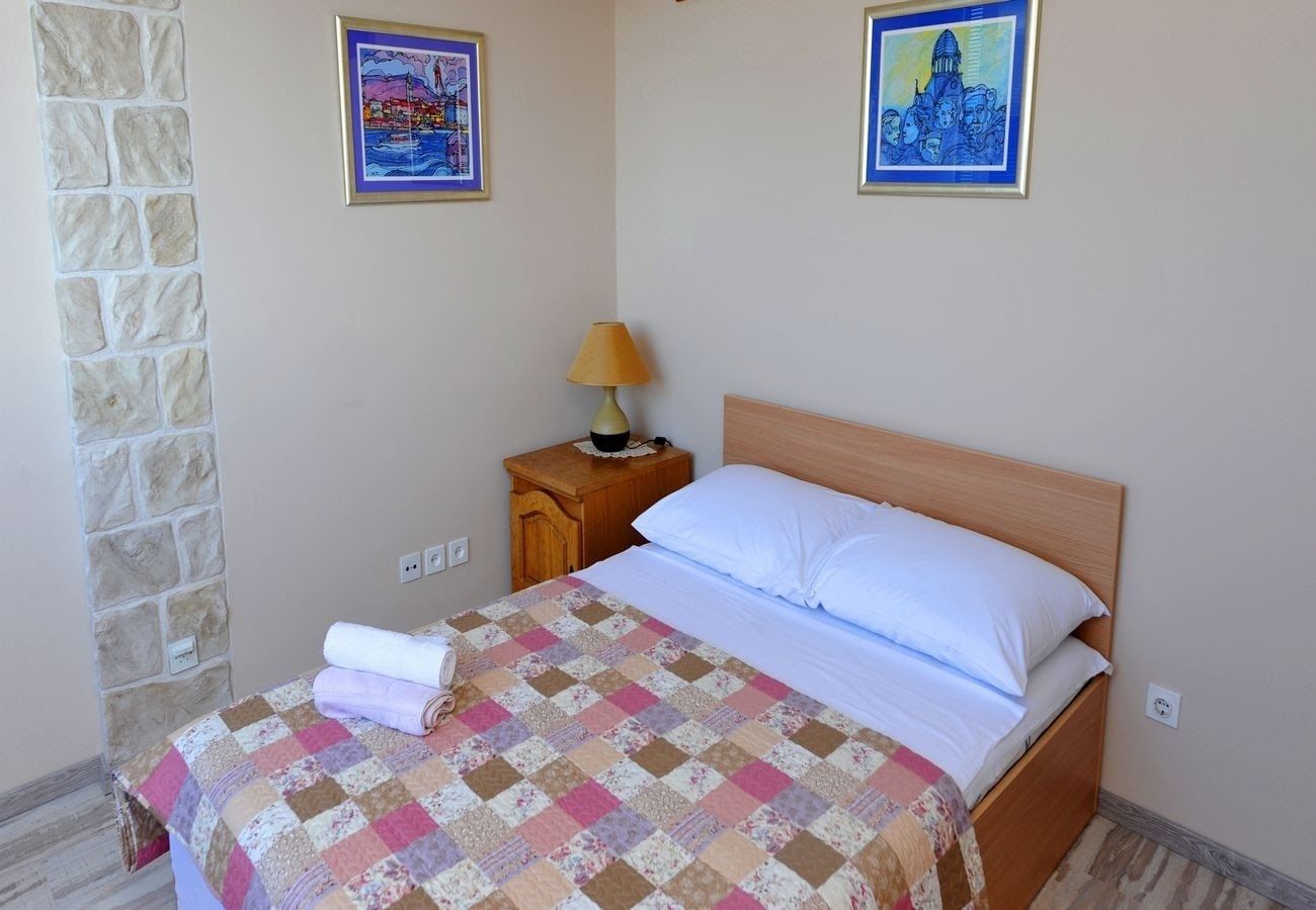 A bedroom with a wooden bed, a quilt, a nightstand with a lamp, and two framed pictures on the wall.