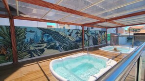A rooftop pool area with two hot tubs, a wooden deck, and a mural of marine life. - Aquarius - Achei Férias (Caldas Novas)