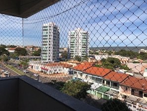 A view through a chain-link fence of a residential area with multiple-story buildings, a road with vehicles, and a clear sky. - Aquarius - Achei Férias (Caldas Novas)