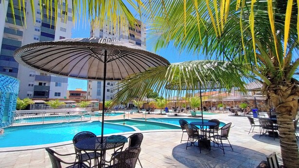 A pool area with multiple pools, lounge chairs, and umbrellas. - Aquarius - Achei Férias (Caldas Novas)
