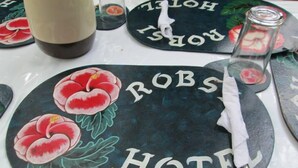 Une enseigne d’hôtel avec l’inscription « ROB’S HOTEL » et un motif floral.