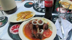Une table à manger avec des assiettes remplies de nourriture, une bouteille de Coca-Cola et une carafe.