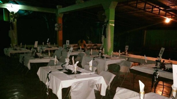 Un restaurant où les tables sont dressées pour le service, recouvertes de nappes blanches et disposées en rangées.