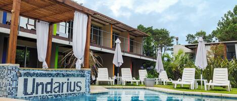 Una piscina al aire libre de temporada, sombrillas, tumbonas