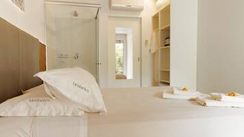 Una habitación de hotel con cama, ducha y vistas al exterior.