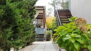 A pathway leading to a building with a wooden staircase and a covered outdoor seating area. - Undarius Hotel - Clothing Optional Hotel Exclusively for Gay Men (Chihuahua)