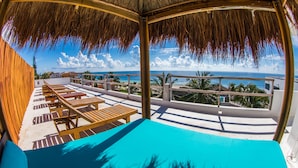 A beachside lounge with wooden tables and a pool, overlooking the ocean and palm trees. - Hotel Ojo de Agua (Puerto Morelos)