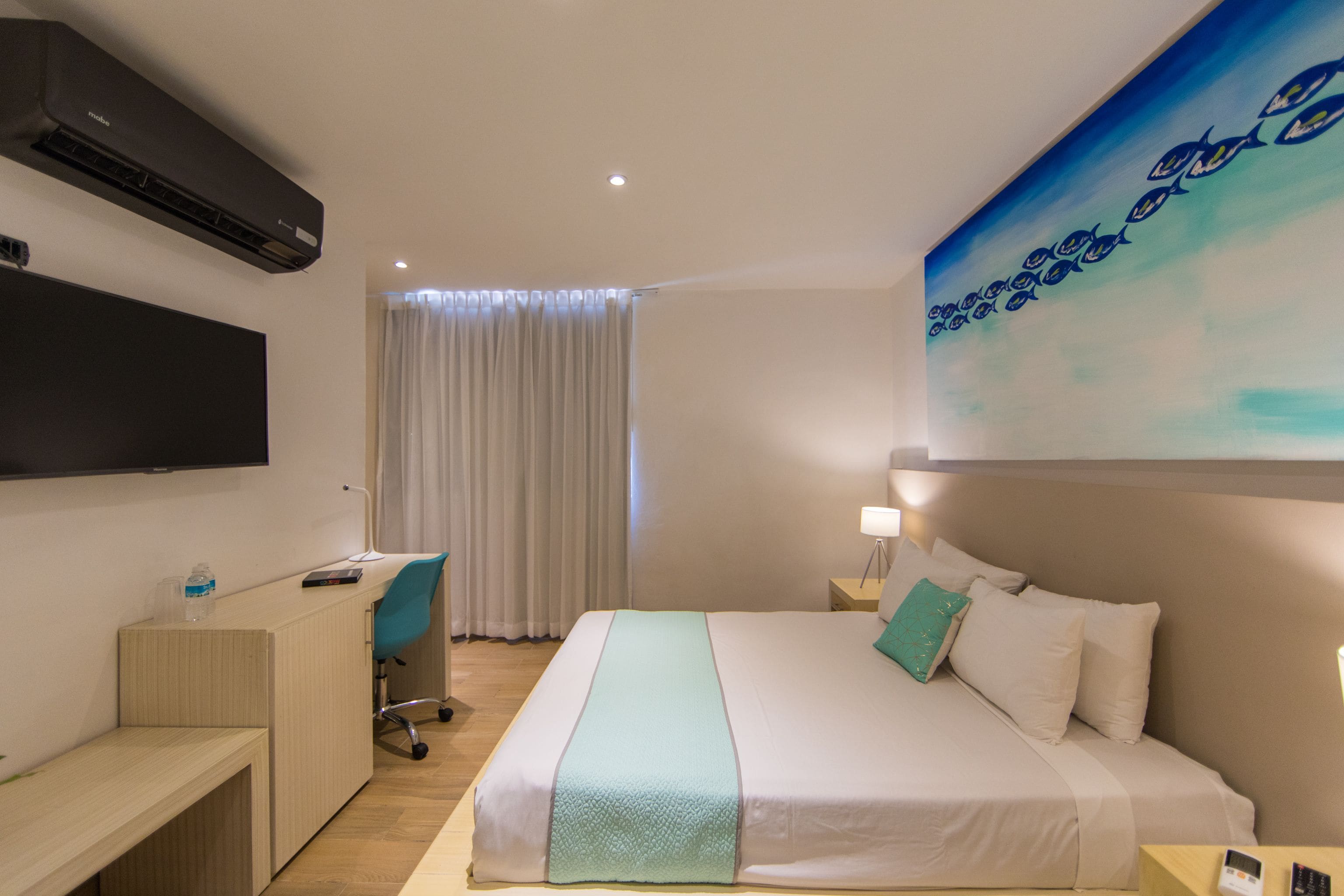 Une chambre d’hôtel avec un lit, un bureau, une chaise, une télévision et un tableau au mur.