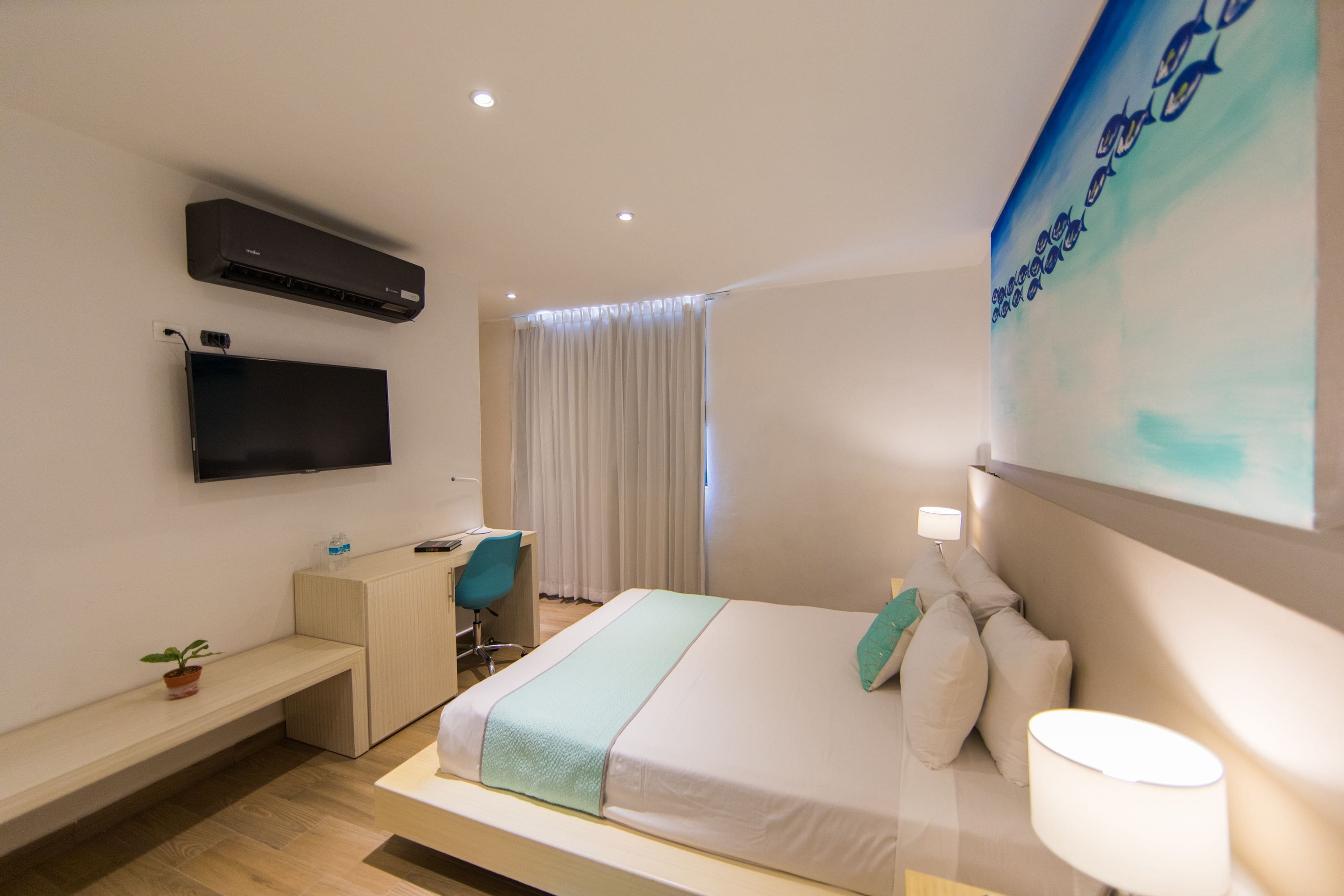 A modern hotel room with a bed, desk, and flat-screen TV.