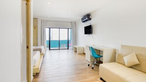 A hotel room with a bed, a sofa, a desk, a chair, and a TV on the wall. - Hotel Ojo de Agua (Puerto Morelos)