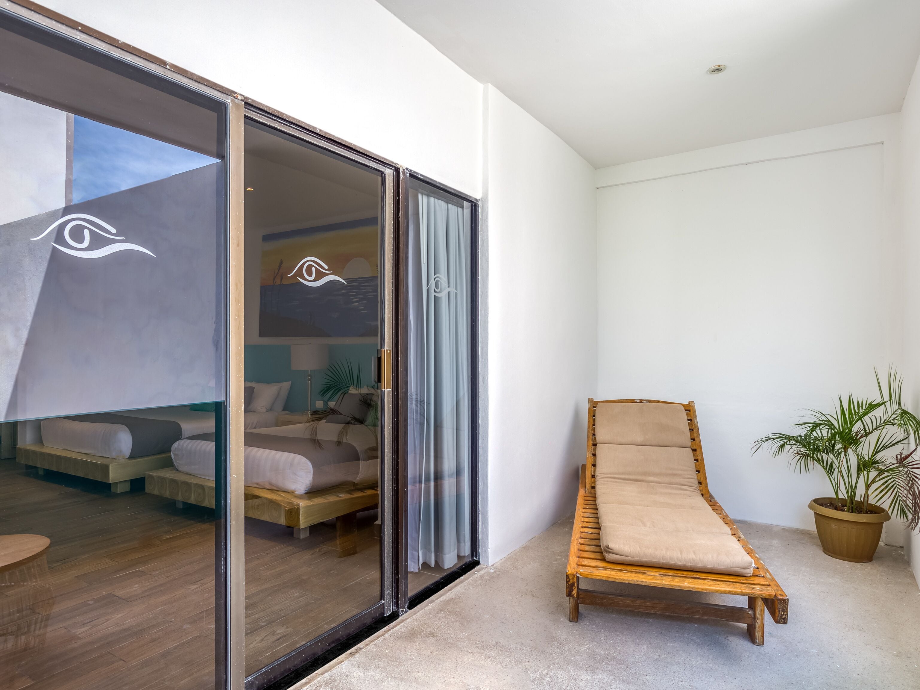 A room with a bed, a wooden chair, and a potted plant.