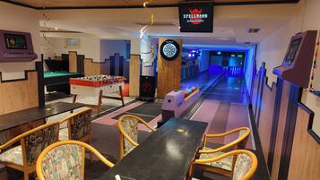 A billiards room with a foosball table, pool table, and dartboard.