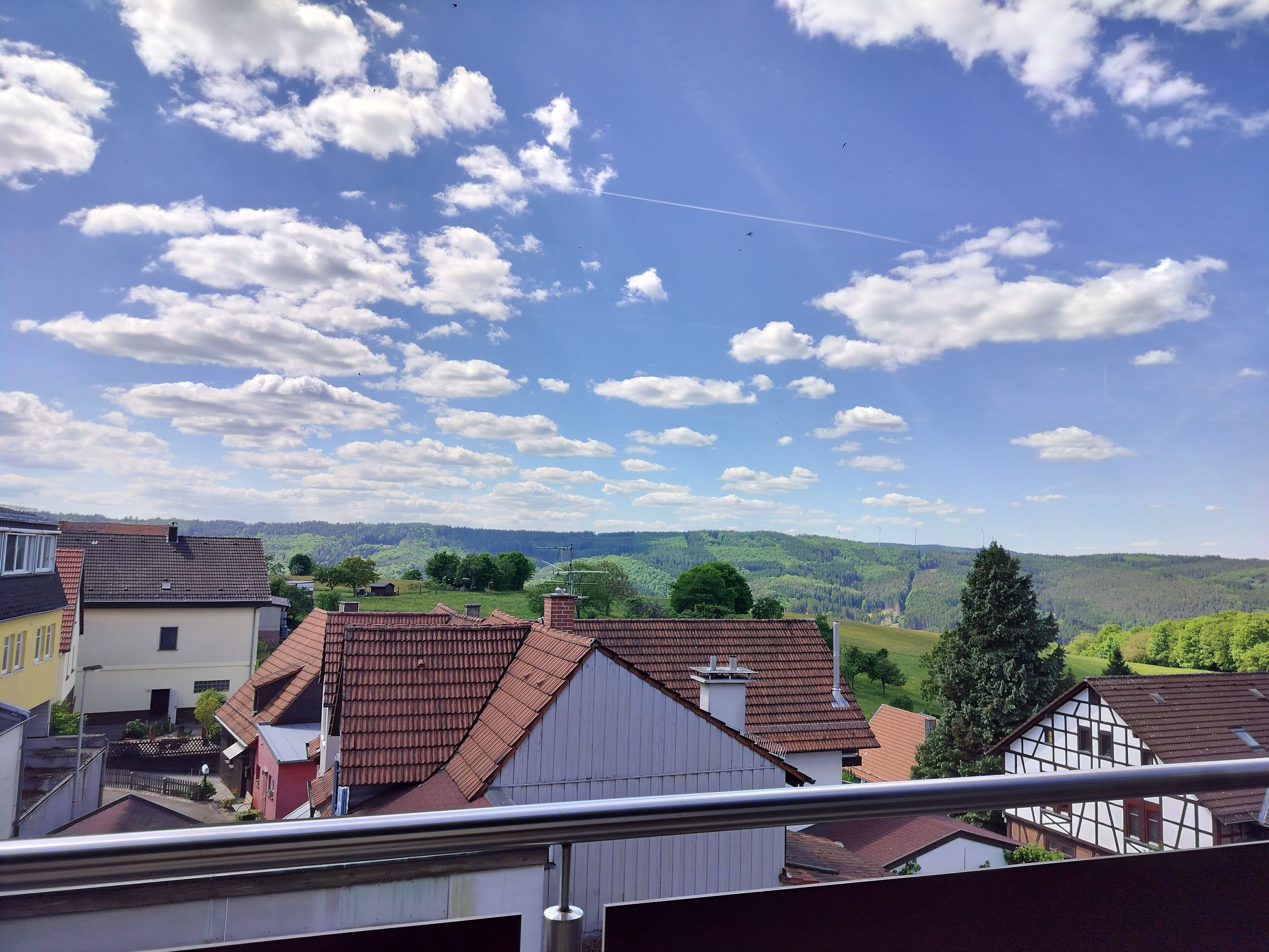 A residential area with houses, a clear sky, and a distant hilly landscape.
