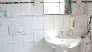 Un baño con lavamanos blanco, inodoro y espejo.