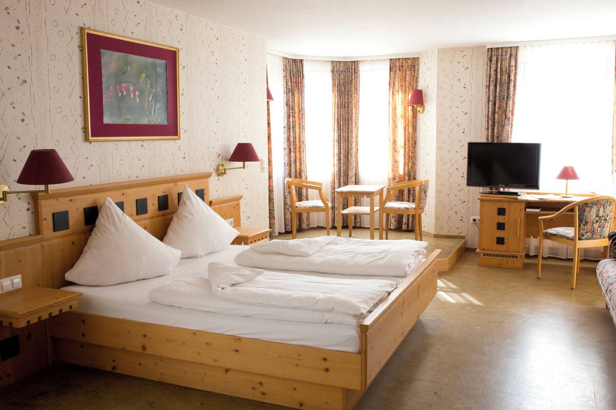 Camera d'albergo con un letto grande, due comodini, una televisione e una piccola scrivania con una sedia.