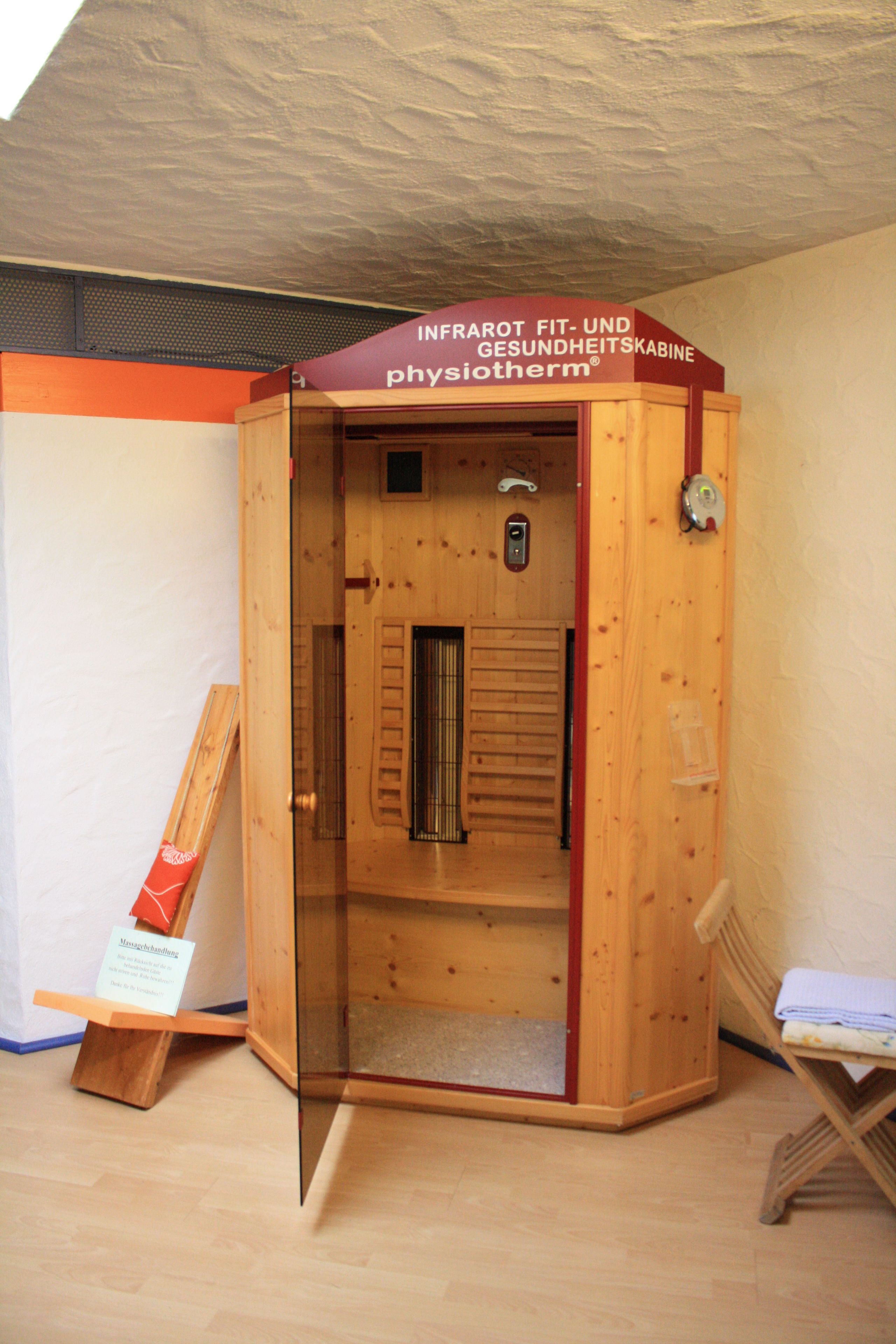 A wooden sauna with a red and white sign, a wooden bench, and a small table.