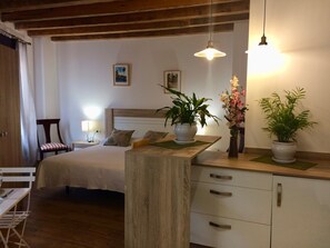 Une chambre à coucher avec un lit, une table de chevet, une lampe et deux plantes en pot.