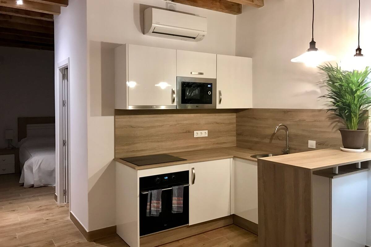 A compact kitchen with white cabinets, a built-in oven, a microwave, and a sink.
