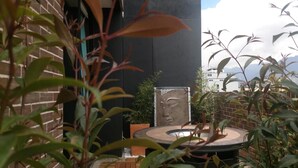 A courtyard with a round table, potted plants, and a decorative wall. - De Película Apartasuites (Bogotá)